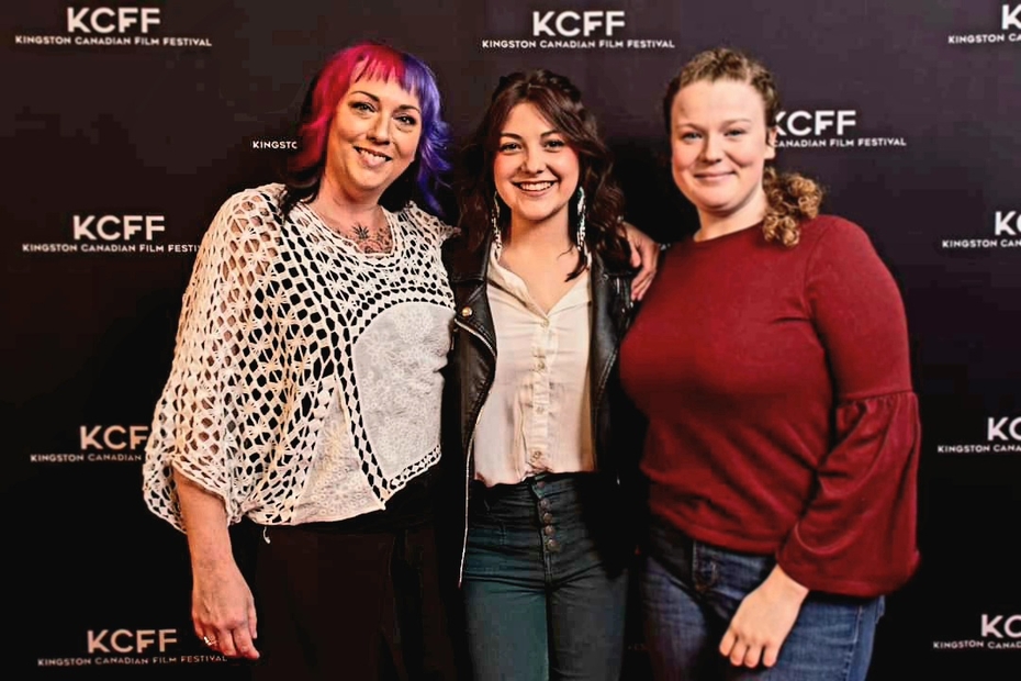 Paula Dickson, Hairstyling Program Coordinator, and Hairstyling graduates Julia Gutz and Cassidy Phieffer stand in front of the Kingston Canadian Film Festival backdrop